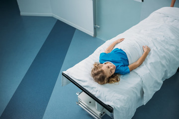 overhead view of kid lying on medical stretcher in corridor