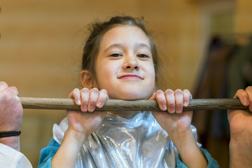 little girl pulling herself up on a wooden crossbar