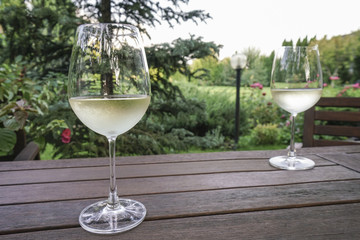 white wine glasses on wooden table at garden