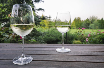 white wine glasses on wooden table at garden