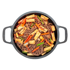 Delicious buckwheat noodles with tofu skin and vegetables in a cast iron wok isolated on white background closeup