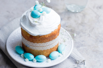 Easter cake kulich. Traditional Easter sweet bread decorated blue candy cane shape eggs on plate on gray stone table background. Copy space.