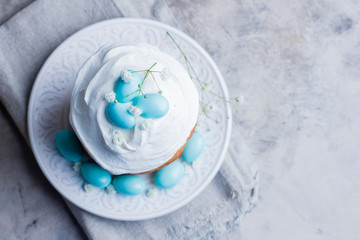 Easter cake kulich. Traditional Easter sweet bread decorated blue candy cane shape eggs on plate on gray stone table background. Copy space, top view