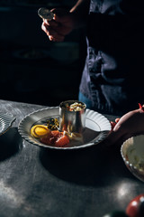 Fototapeta na wymiar cropped shot of chef preparing salad with metal forming tube at restaurant