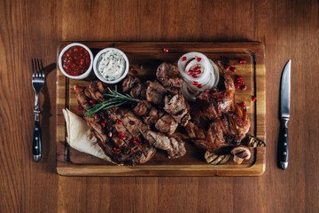 Fototapeta na wymiar assorted grilled meat served on wooden board with sauces