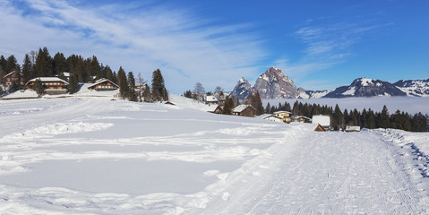 Fototapeta na wymiar View in the village of Stoos in Switzerland in winter with summits of the Kleiner Mythen and Grosser Mythen mountains rising from sea of fog