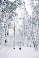 rear view of woman taking photo of snowy forest by smartphone