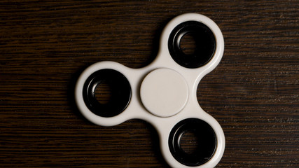 White spinner is spinning on the table. Spinning in motion of a popular white toy spinner on a...