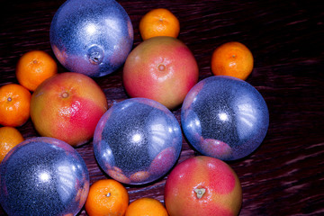 Tangerines, clementines on blue plate. Blue scarf, gray background. Christmas balls.