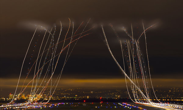 Light paintings over airport against cloudy sky in city at night