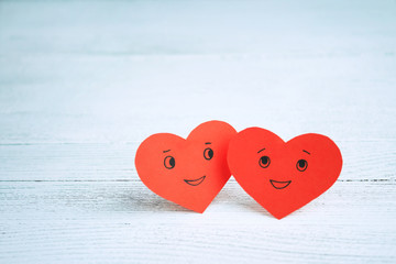 Fototapeta premium Two red smiling hearts on a light background. St. Valentine's Day. Couple in love.