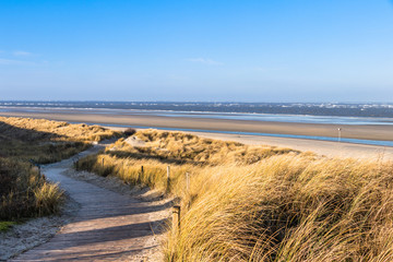 Weg durch die Dünenlandschaft zum breiten Strand auf der Nordseeinsel Spiekeroog im Winter