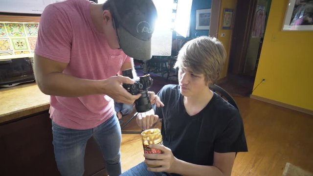 Teen filmmaker on set shooting into a jar of peanut butter with a large light behind him.
