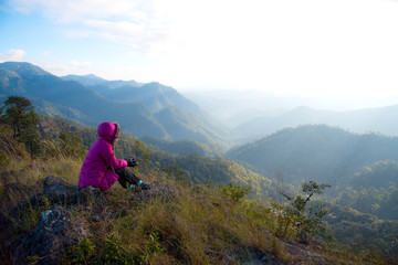 Fototapeta premium Woman tourism vacation and travel. Tourist woman in camping site sitting and enjoying mountains landscape at winter mountain in Chiangmai, Thailand. 