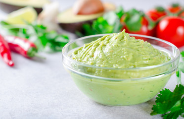 Traditional mexican homemade guacamole sauce in a glass bowl and