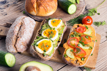 Sandwiches with avocado, eggs and tomato on a wooden background. Fresh organic vegetables, eggs and whole wheat bread. Healthy breakfast. Retro style.