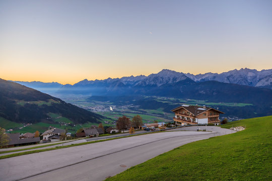 Aufnahme über den Ort Weerberg in Tirol mit dem Inntal und dem Karwendelgebirge im Hintergrund fotografiert am Abend bei untergehender Sonne im Juni 2014