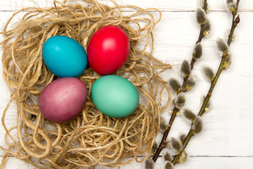 Easter background with eggs, nest and catkins on wooden background, copy space