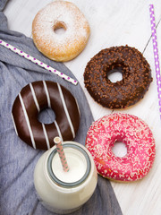 Bottle of milk and colorful donuts with chocolate and icing, selective focus