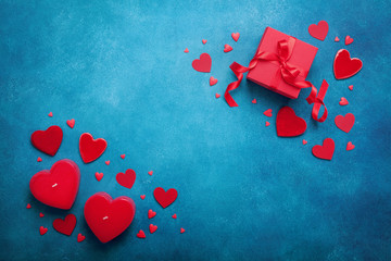 Holiday background with gift box and red hearts on blue table top view. Valentines day card. Flat...