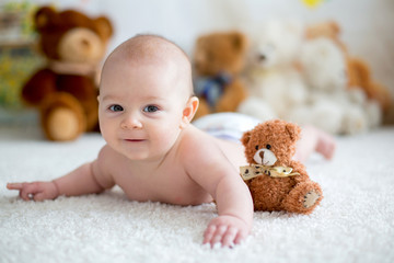 Little baby boy playing at home with soft teddy bear toys