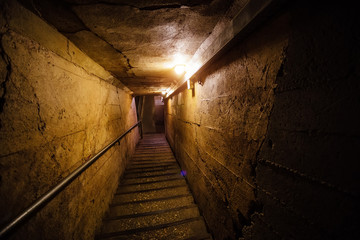 Dark corridor of old underground Soviet military bunker under artillery fortification. Staircase goes down 