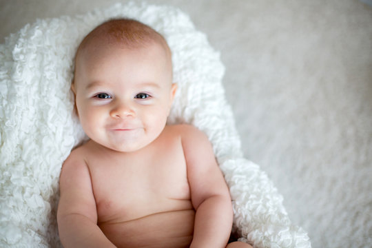 Little baby boy playing at home with soft teddy bear toys