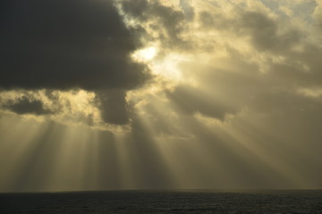 Fototapeta na wymiar Sunburst, Bay of St Malo. Telephoto image of clouds shot from Jersey pointing toward France.