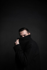 Portrait of a stylish young man in a black coat. Black background.