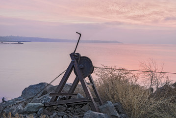 Coastline of the sea. An old rusty winch on an abandoned pier.