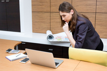 Businesswoman thinking with construction plan and notebook.