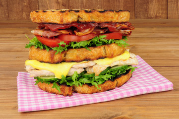 Chicken and bacon double decker sandwich on a wood background