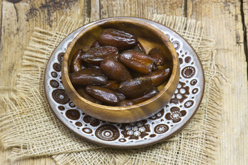 dried dates in a bowl on wooden background