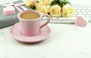 Valentine's day concept. Pink cup with cocoa, a bouquet of beautiful roses, a keyboard and a gift with pink hearts. Copy space