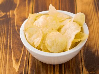 potato chips in white bowl on brown wooden table