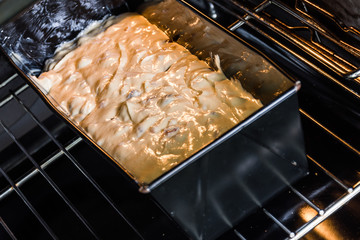Cake batter and dough in a black baking form placed in a modern electric baking oven in a new home kitchen. - 186578398