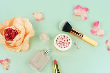 Obraz na płótnie Canvas Makeup cosmetic accessories products pearl make up powder and brush, lipstick, perfume, flowers on pale grey background. Flat lay. Top view. Copy space