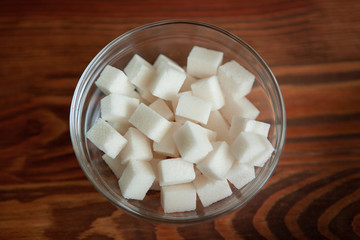 White sugar cubes in glass bowl on wooden table