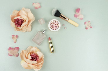 Makeup cosmetic accessories products pearl make up powder and brush, lipstick, perfume, flowers on pale grey background. Flat lay. Top view. Copy space 