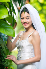 The bride take photo with a ring in the garden.