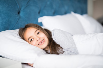 Cute beauty little girl lying in bed at home