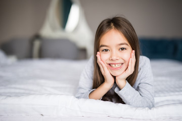 Adorable smiling little girl waked up in her bed at home