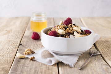 Healthy breakfast with oats granola,raspberry and nuts over wooden table