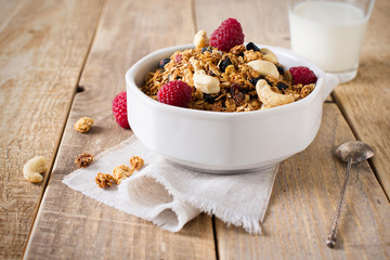 Healthy breakfast with oats granola,raspberry and nuts over wooden table