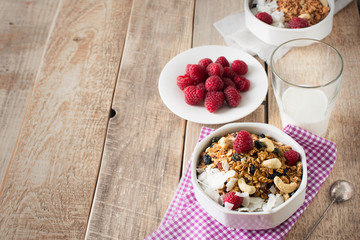 Healthy breakfast with oats granola,raspberry and nuts over wooden table