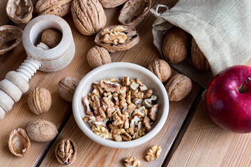 Shelled and unshelled walnuts on a wooden table with a nutcracker