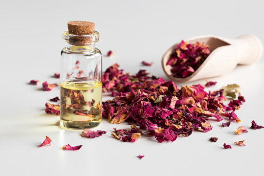 A bottle of rose essential oil with dried rose petals