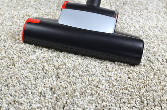 Vacuum cleaner dust brush on grey shaggy carpet surface