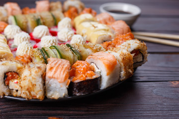 Sushi restaurant menu, Japanese food, delicious seafood concept. Great delicious set of tasty colorful sushi rolls served on the plate with soy sauce and chopsticks, close up, selective focus