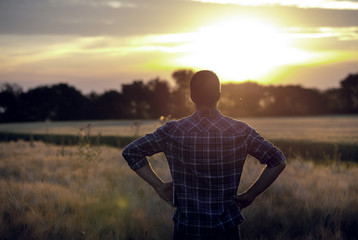 Rear view of farmer in field at sunset